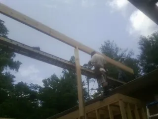 Carpenter setting a ridge beam over a new addition frame — Ice Dam Removal by Roofing Brothers in Casar