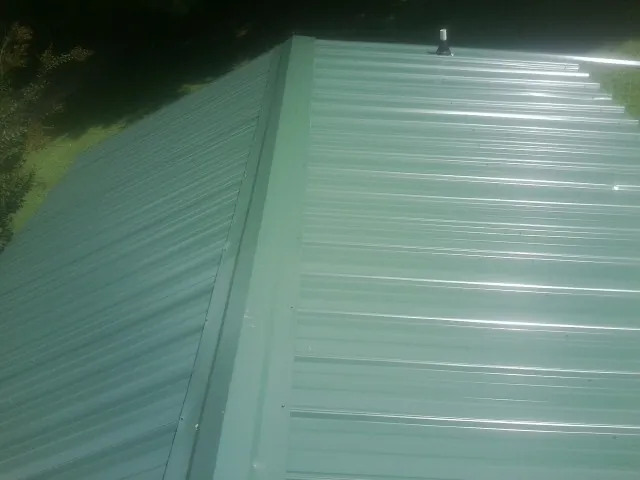 New green metal panels meeting at the ridge of a roof — Flat Roof Repair work by our crew in Casar