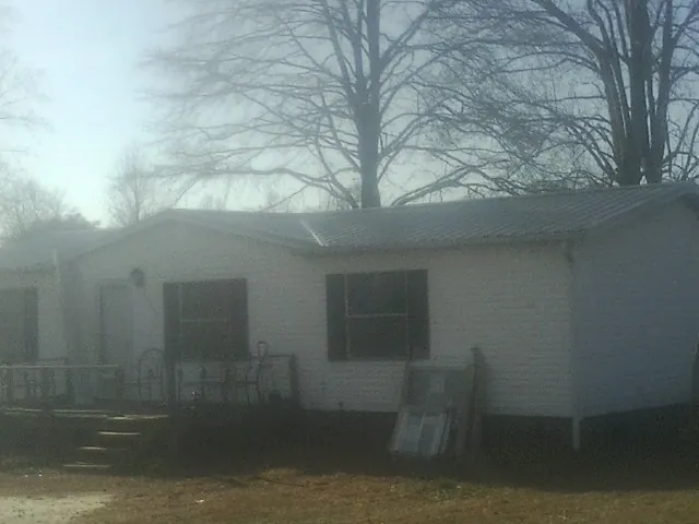 New metal roof on a white painted brick home on a foggy morning in Casar