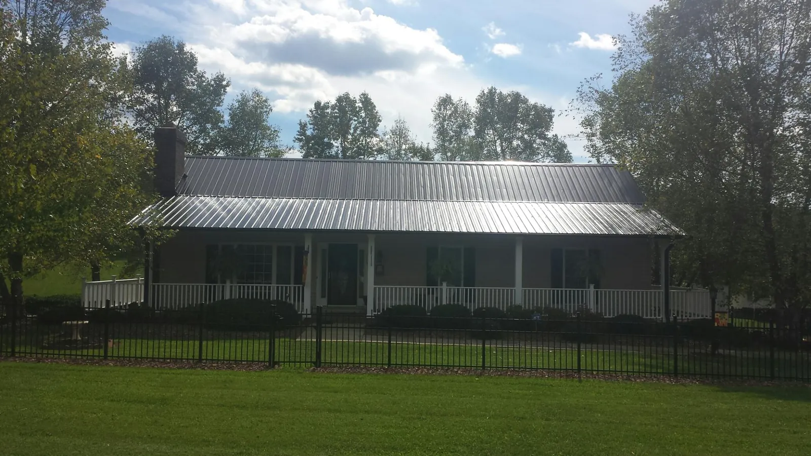 Gray metal roof on a brick ranch with a full width front porch — Gutter Guard Installation work by our crew in Casar