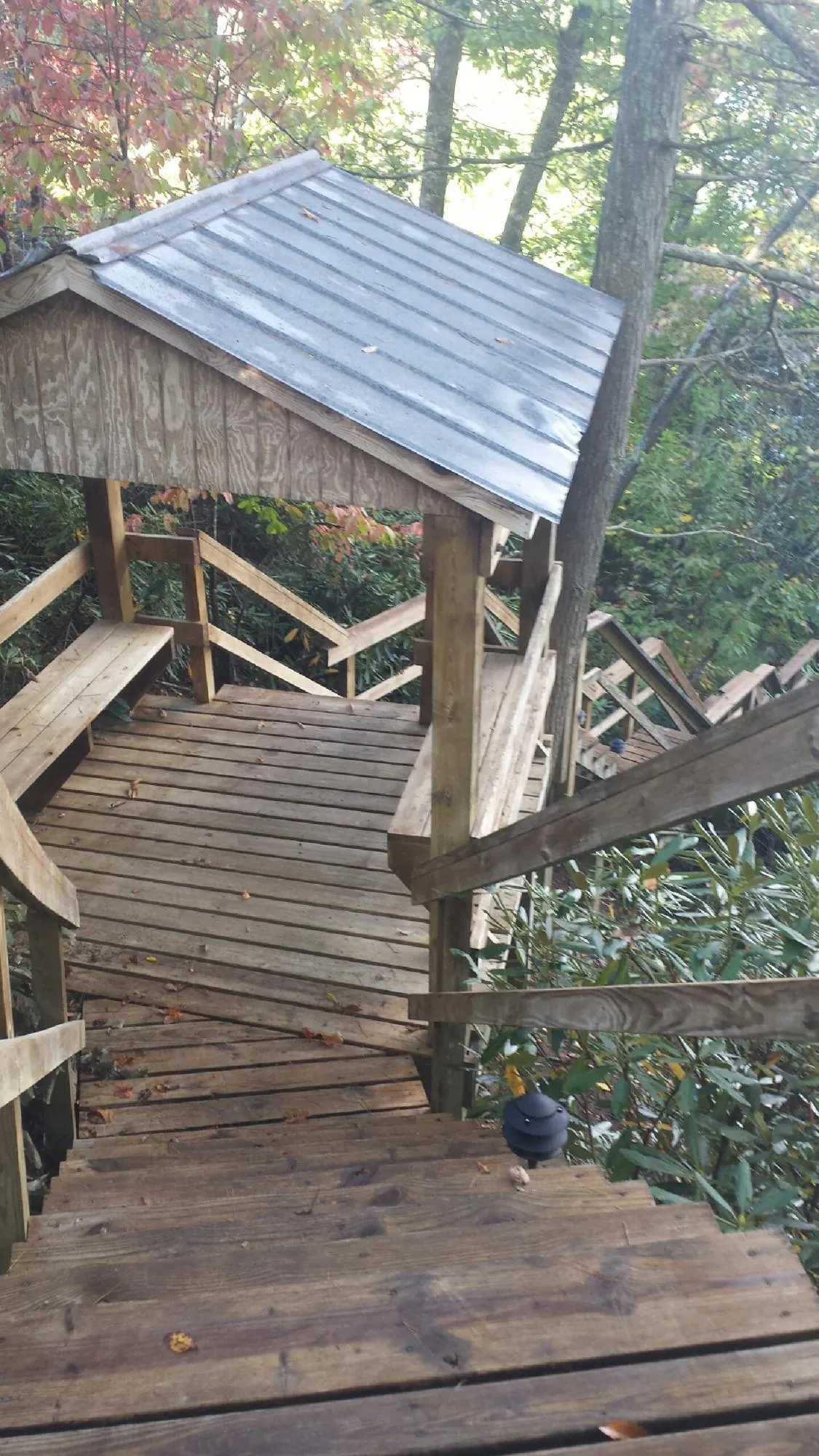 Metal roofed shelter over wooden steps on a wooded walkway — Skylight Repair & Installation work by our crew in Casar