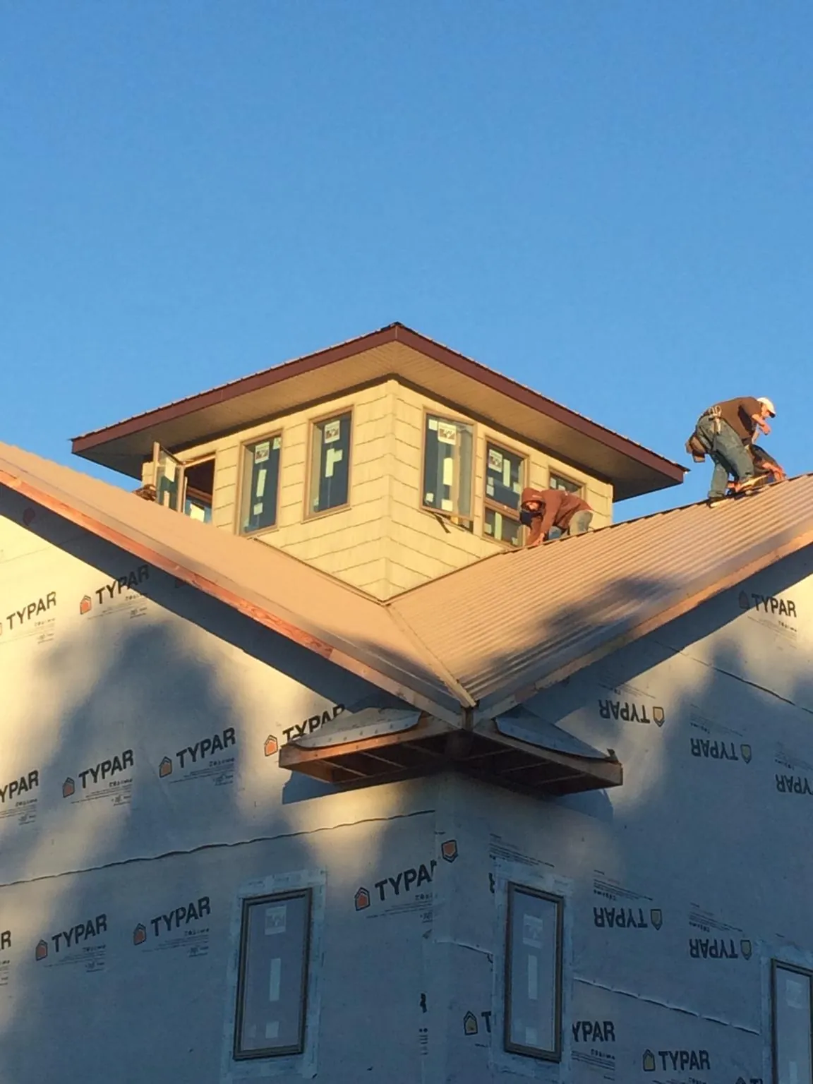 Roofers working around a rooftop cupola on a new metal roof at sunset — Roof Waterproofing in Casar by Roofing Brothers